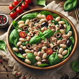 A fresh tuna white bean salad with spinach, olives, and basil, served in a large bowl